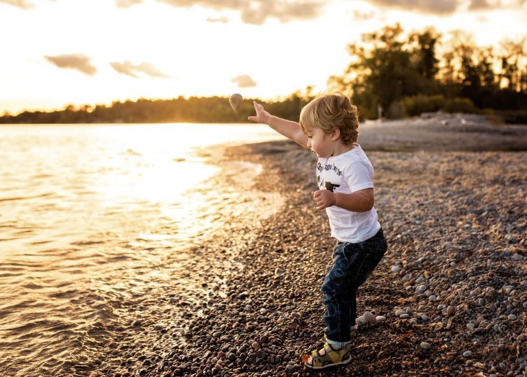 young boy throwing rocks into the lake
