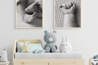 Baby furniture in a nursery with 2 framed images of baby hand and feet on the wall