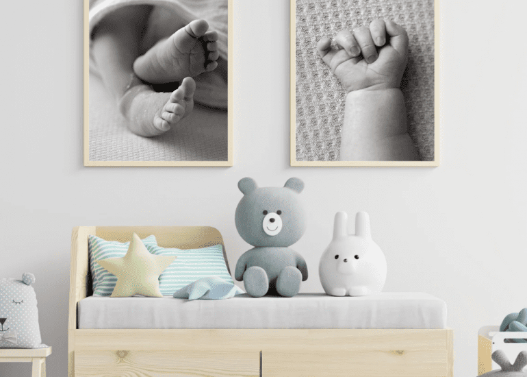 Baby furniture in a nursery with 2 framed images of baby hand and feet on the wall