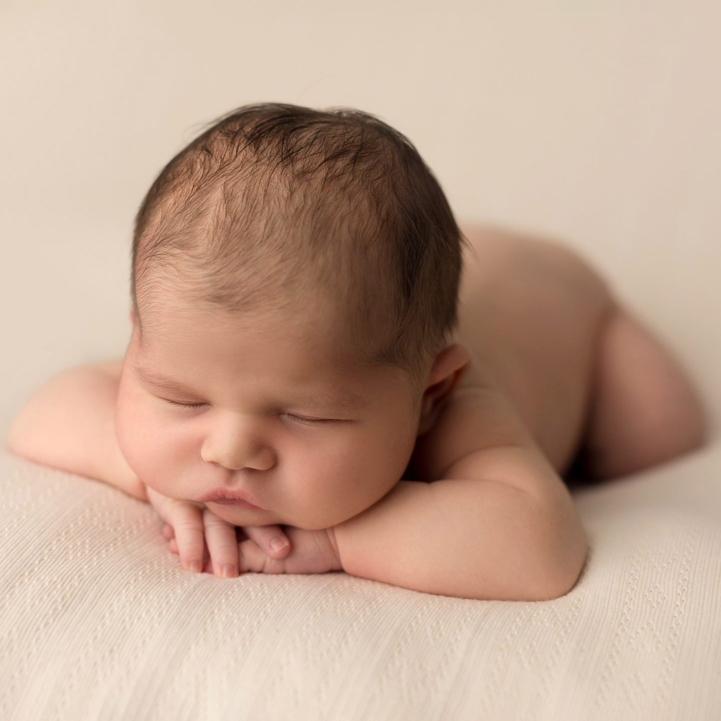 newborn baby with head on hands