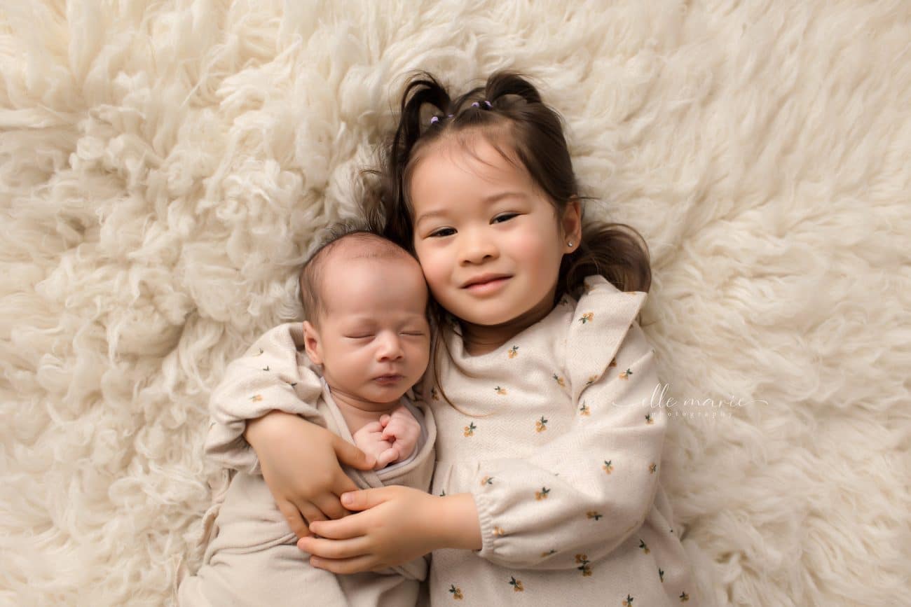 newborn baby snuggling with his siter