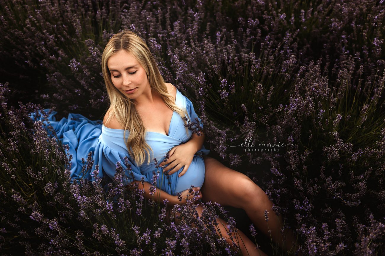 a pregnant woman lays in a field of lavender
