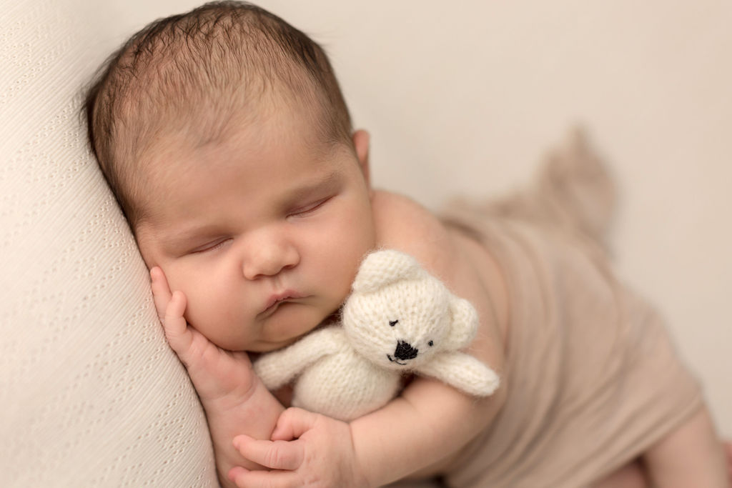 A newborn baby cuddles with a white teddy bear in a studio while sleeping after visiting baby store oshawa