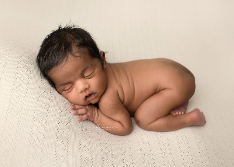 A newborn baby sleeps naked on its belly in a studio on a white heart pattern blanket after prenatal yoga whitby