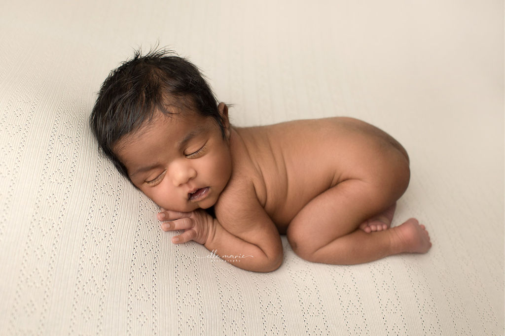 A newborn baby sleeps naked on its belly in a studio on a white heart pattern blanket after prenatal yoga whitby